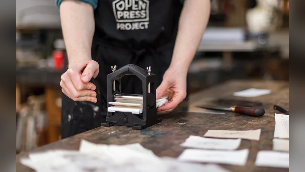 Printmaker using a small black Open Press Project etching press in a workshop